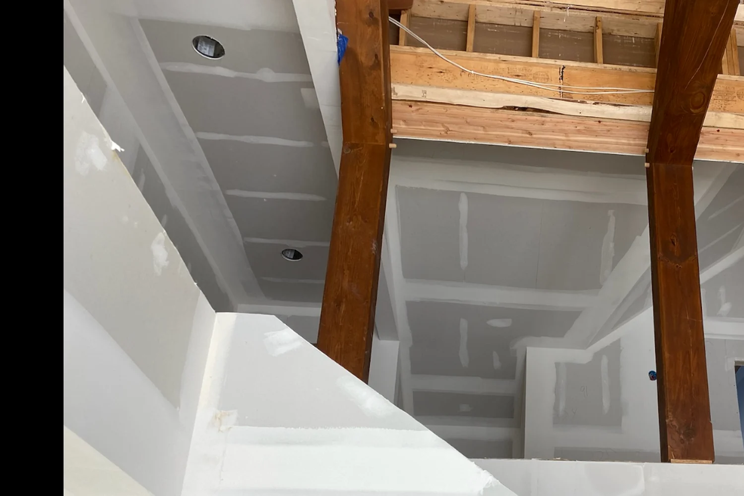 Complex custom drywall installation around beams, stairs, and multiple planes